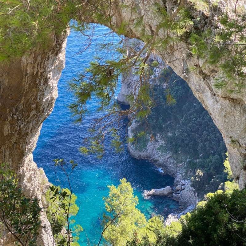 L'Arco Naturale che incornicia una baia turchese sulla costa orientale di Capri