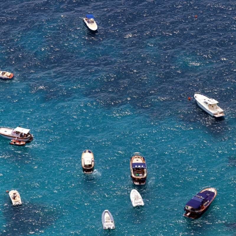 Vista aerea di piccole barche all'ancora sul mare blu scintillante al largo di Capri