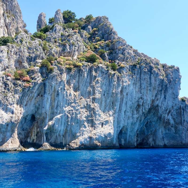 Bianche scogliere calcaree di Capri che si ergono dal mare blu vicino alla Grotta Azzurra