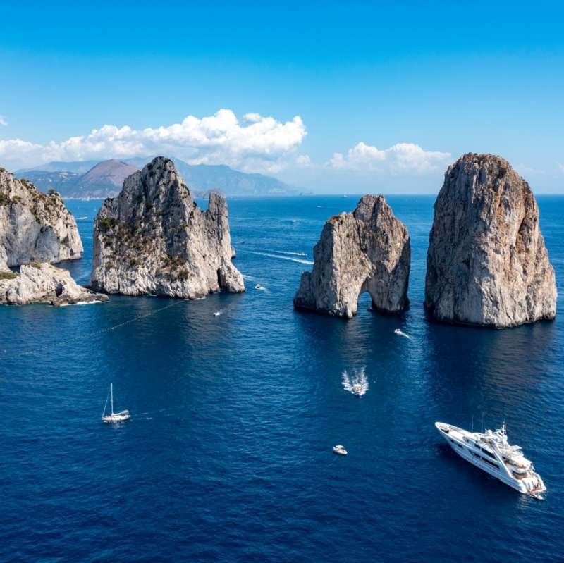 Giro in barca che passa accanto ai tre Faraglioni al largo della costa di Capri