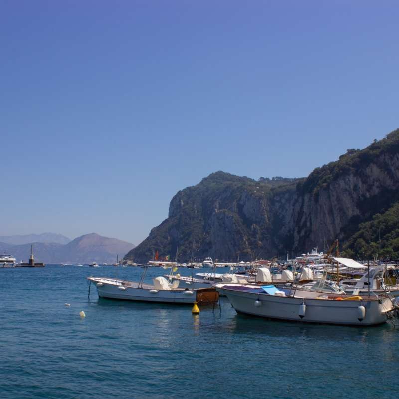 Barche da pesca ormeggiate nel porto di Marina Grande sotto le verdi scogliere di Capri
