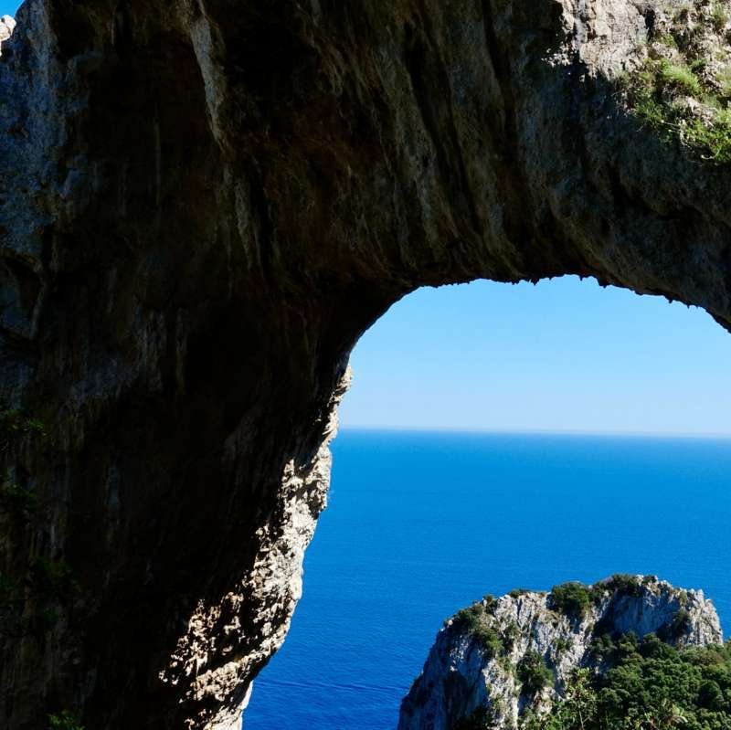 Mare Mediterraneo blu intenso incorniciato dall'arco naturale di roccia di Capri